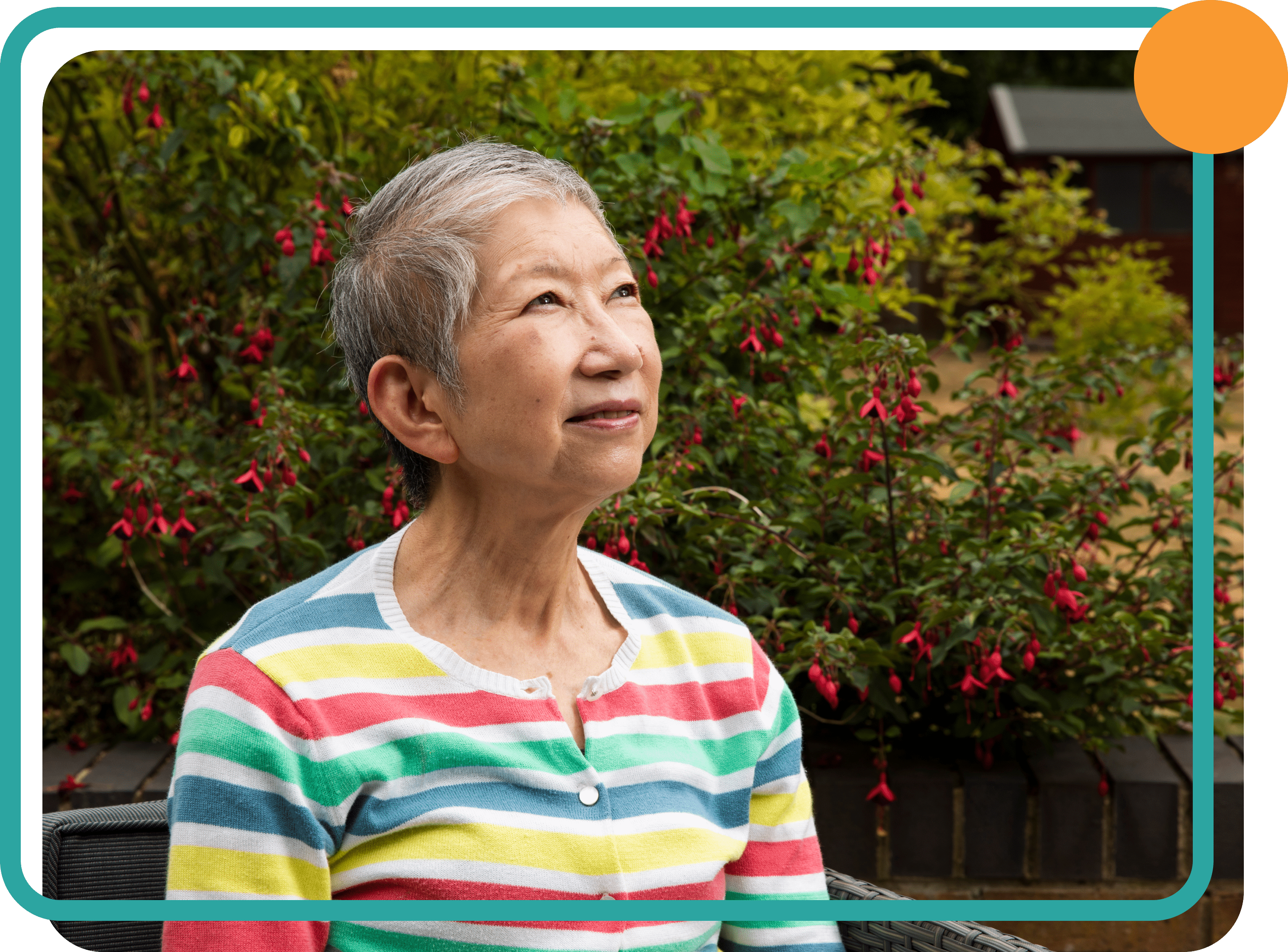 An older lady with short hair wearing a stripey coloured top looking at the sky with trees in the background