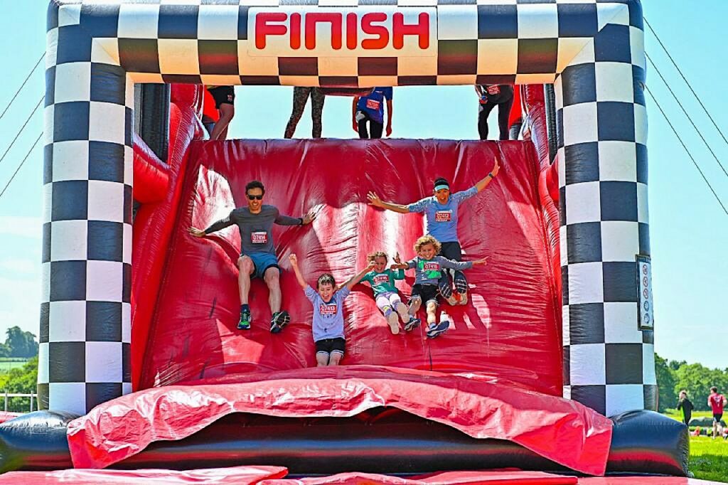 Giant red bouncy castle with 'Finish' sign hanging over and people jumping through the gate