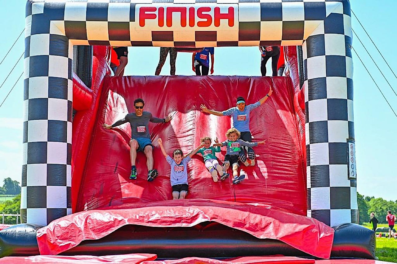 Giant red bouncy castle with 'Finish' sign hanging over and people jumping through the gate