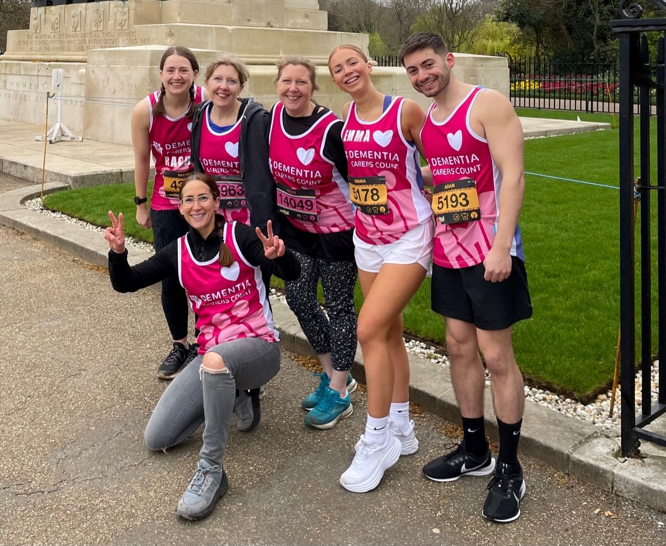 Group of happy athletes wearing Dementia Carers Count purple running vests stand in a group smiling for the camera