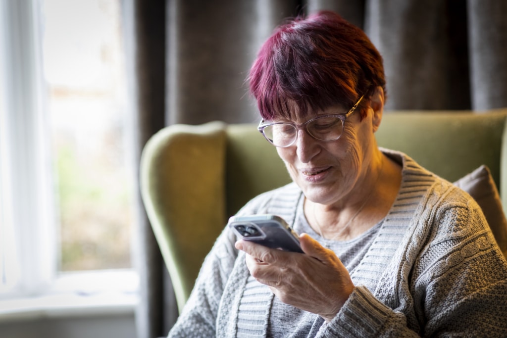 Woman is sitting in a chair looking at her phone