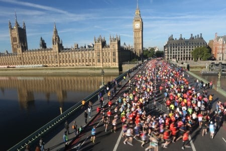 People running over a bridge in London with Big Ben in background