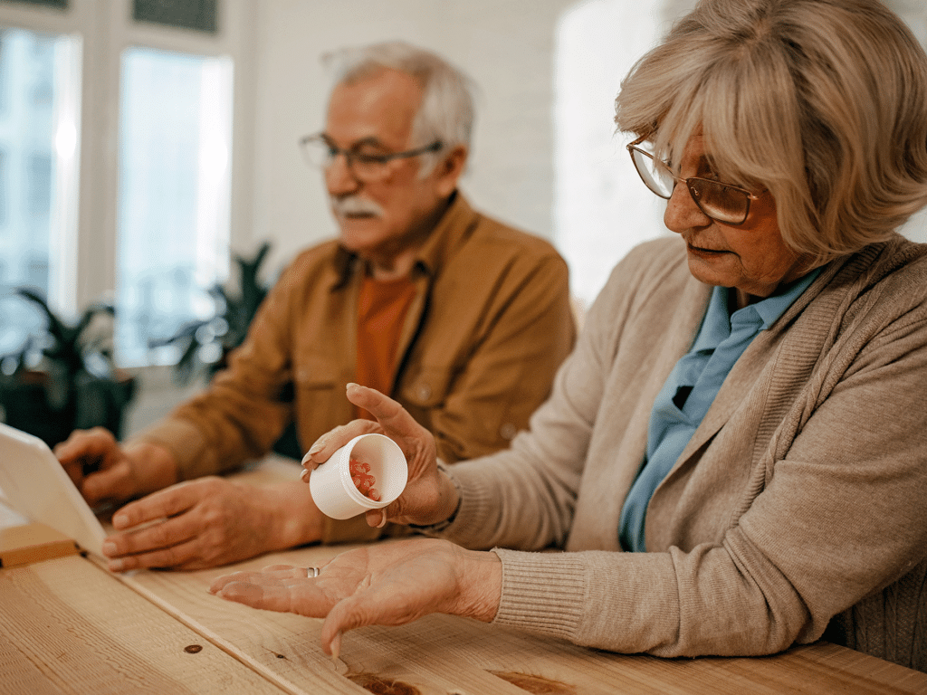 A dementia carer handles medication. Her husband is in the background.