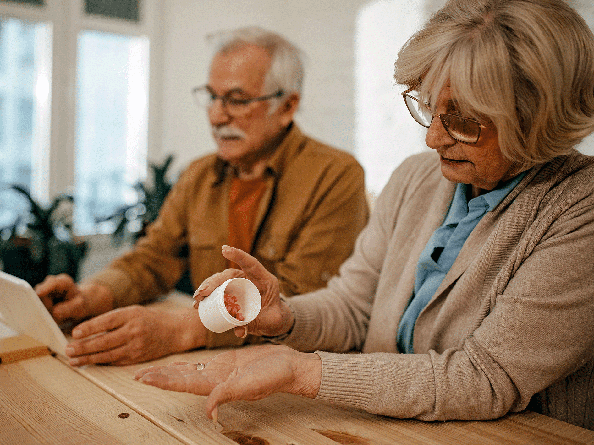 A dementia carer handles medication. Her husband is in the background.