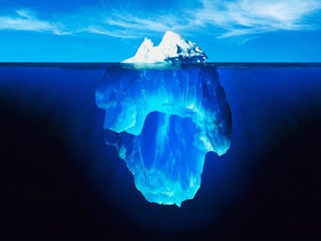 Picture of an iceberg with the tip showing above the water and the rest underneath the waterline.