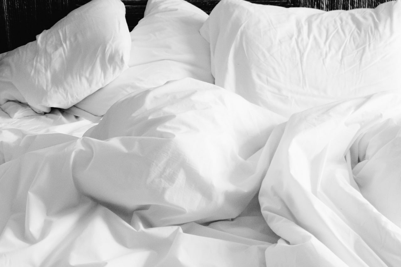 A rumpled set of white pillows and a duvet cover.