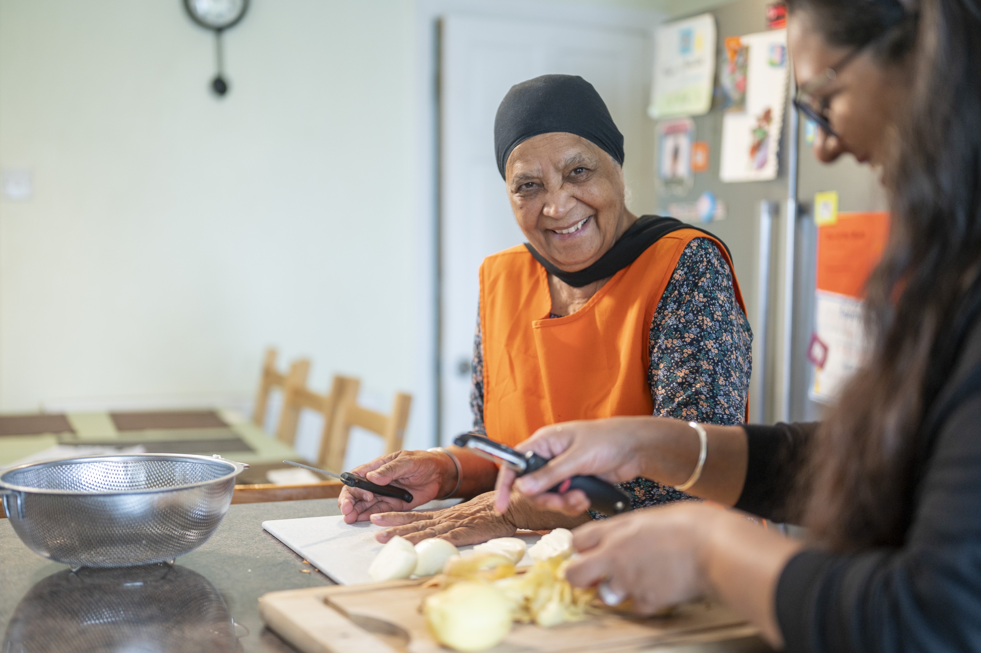 Two women are in the kitchen preparing food together and laughing