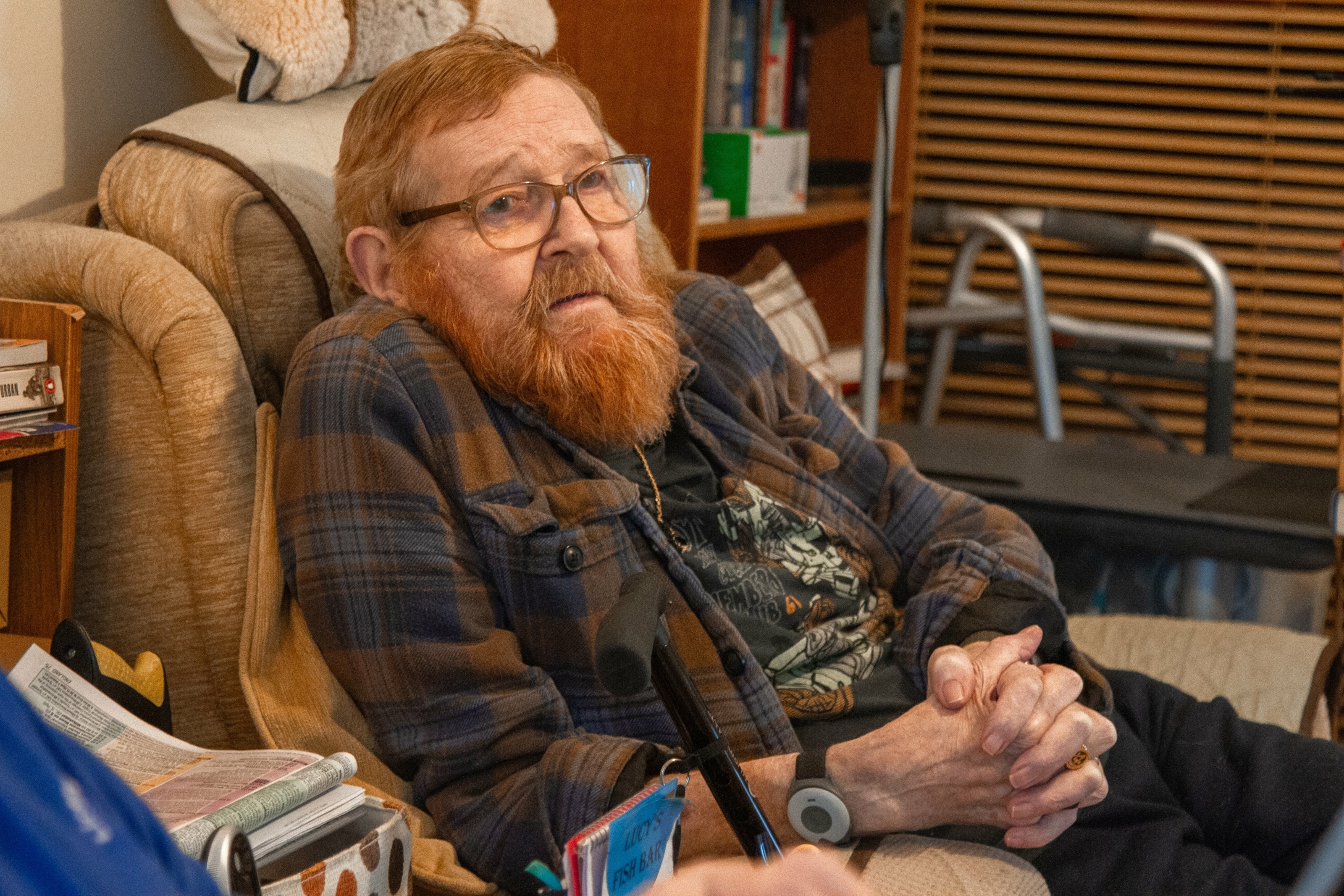 An older man with a beard is sitting in a chair staring straight ahead