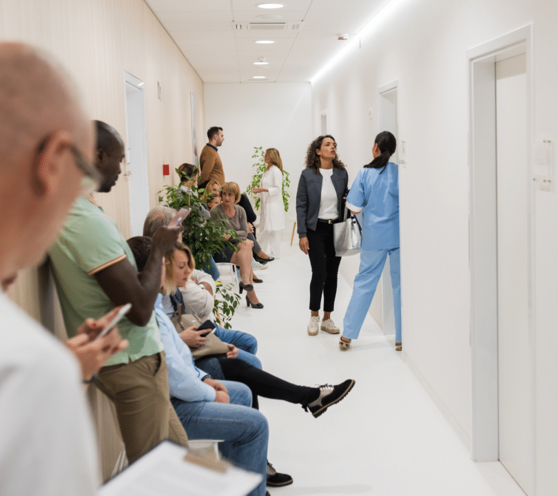 People are sitting in a busy hospital corridor