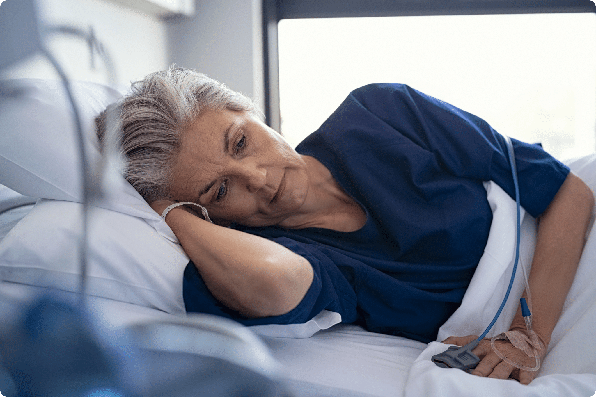 A woman is lying in bed looking very unwell. She has been admitted to hospital in an emergency.
