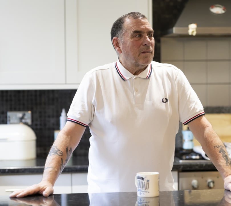 A man in standing in his kitchen looking worried and staring into the distance